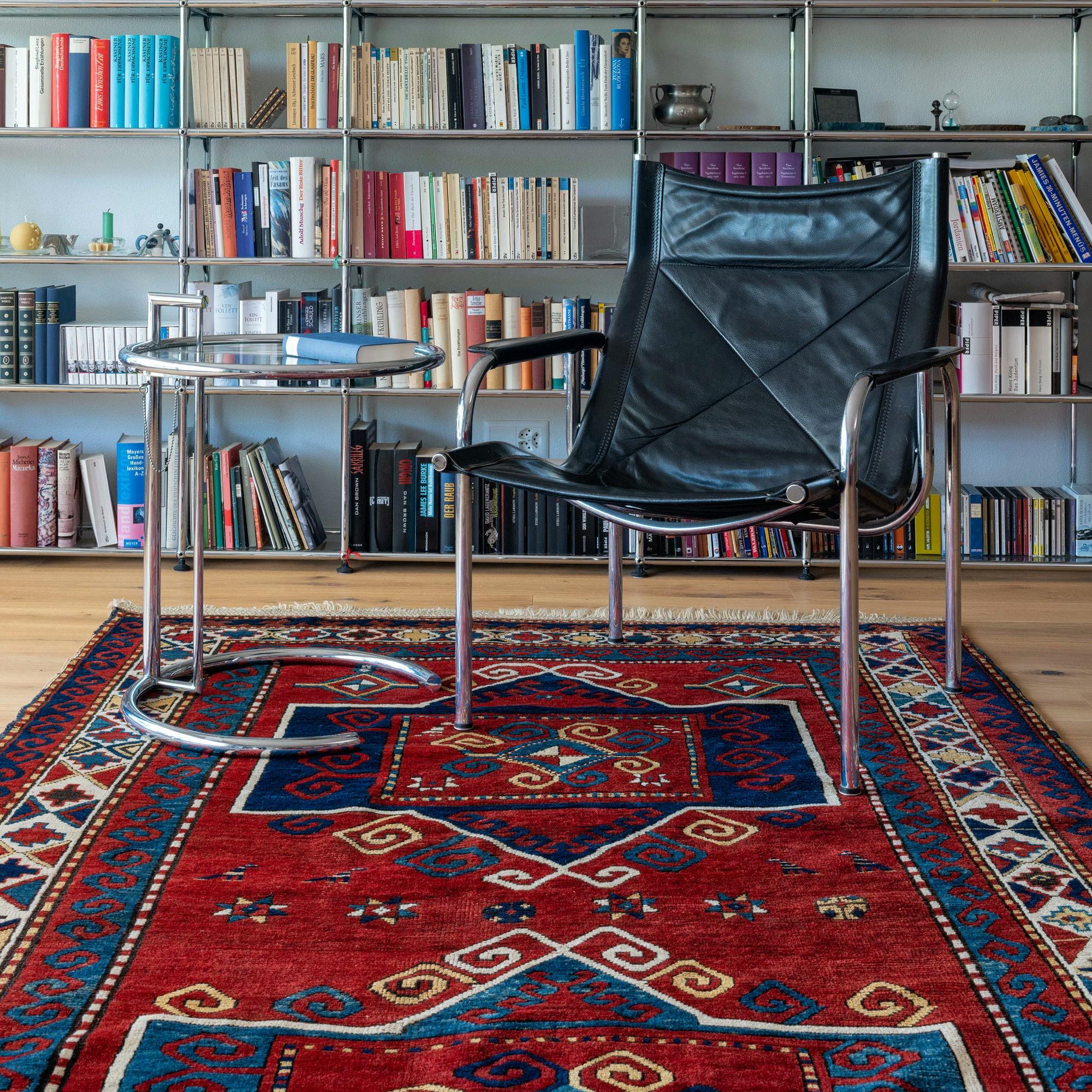 Fachralou Kasak Teppich aus Georgien 250x162 cm, um 1920 mit Sessel und Beistelltisch vor Bücherregal
